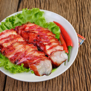 Grilled pork neck on a white plate on a wooden table